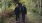 a man and woman walking on a trail in the woods