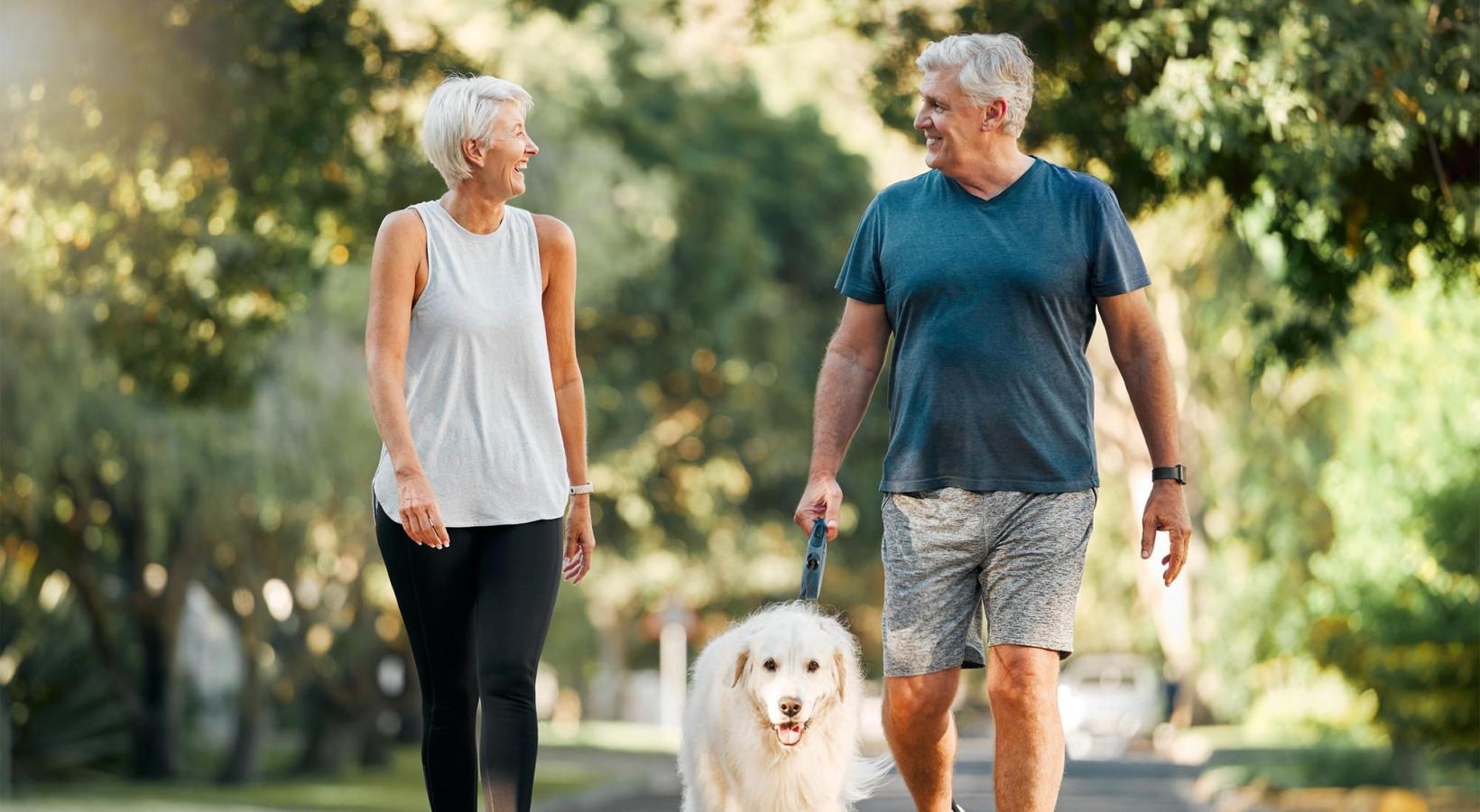 The Residences at McCormick Village is a pet-friendly community! a man and a woman walking a dog on a leash
